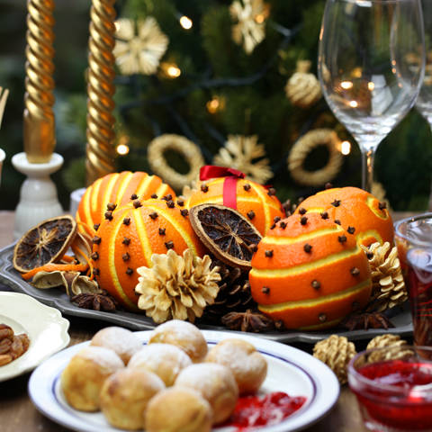 Fint dækket julebord med æbleskiver, gløgg og appelsiner med nelliker.