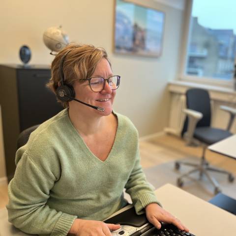 Medarbejder hos Vitus Rejser med telefon-headset sidder klar ved computeren til at tage imod opkald.