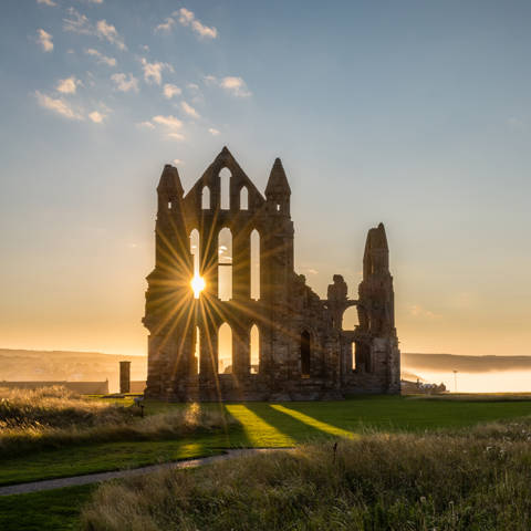 Solopgang ved ruinerne af Whitby Abbey i England.