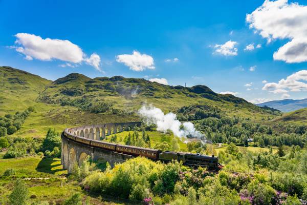 Damptog, der kører på Glenfinnan-viadukten i Skotland.