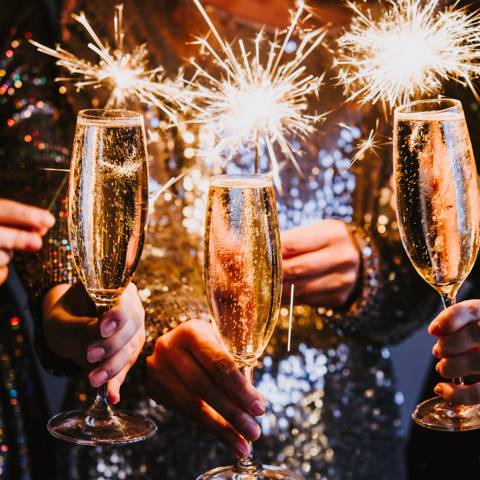 Tre personer skåler med champagneglas og vifter med stjernekastere.