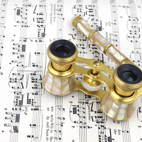 Nærbillede af en teaterkikkert, der ligger på et nodeark.