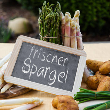 Friske asparges og nyopgravede kartofler og et skilt, hvor der står Frischer Spargel på tysk.