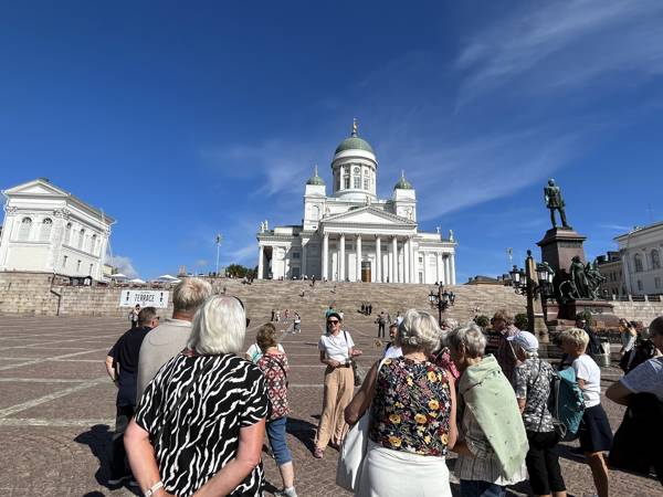 En gruppe gæster lytter til en rejseleder fra Vitus Rejser, der fortæller om domkirken i Helsinki, som de står foran.
