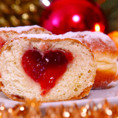 Overskåret Berliner Pfannkuchen med syltetøj i midten i et hul formet som et hjerte.