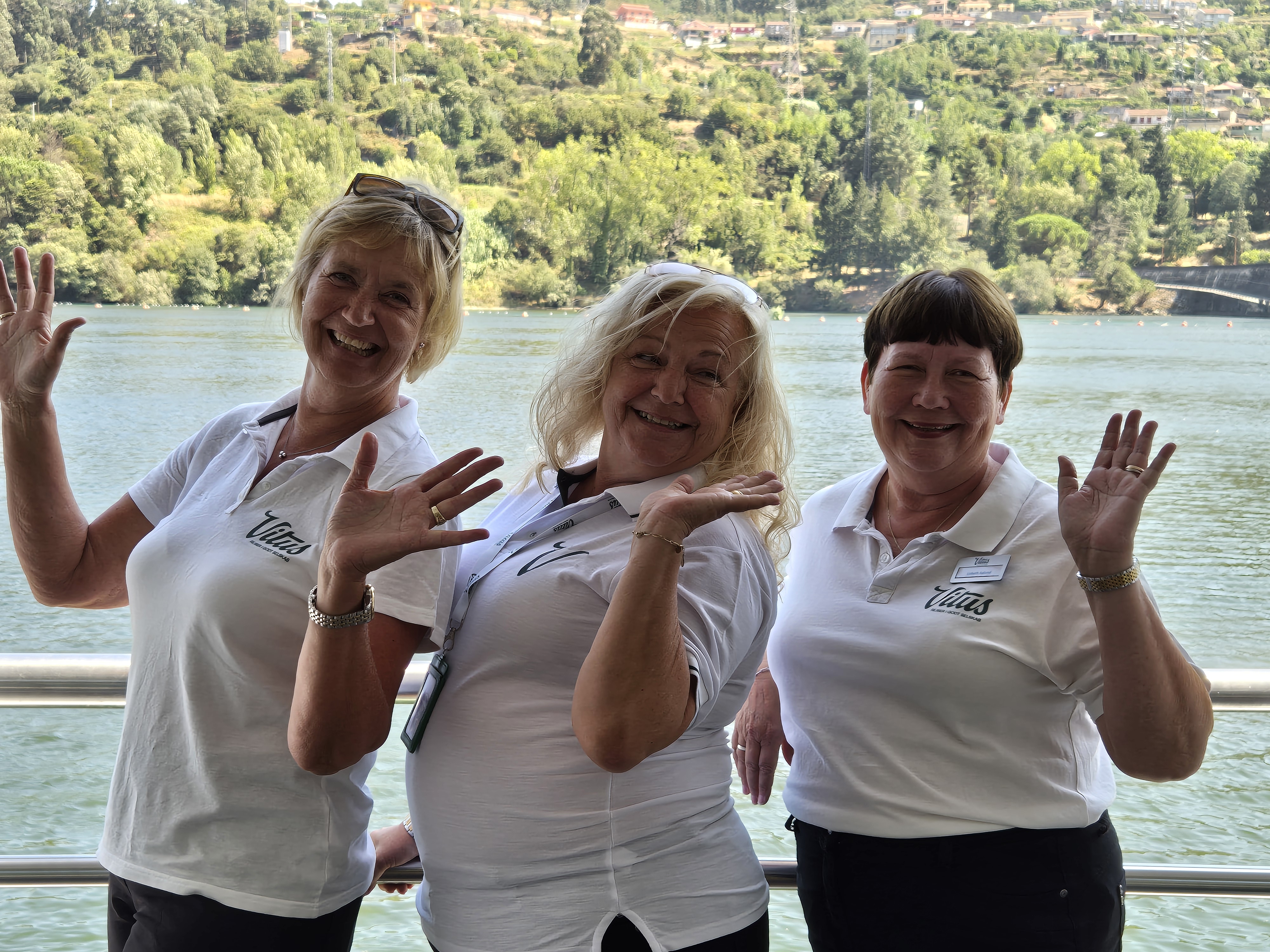 Tre af Vitus Rejsers søde, sjove og glade rejseledere står ved rælingen på et flodkrydstogtskib.