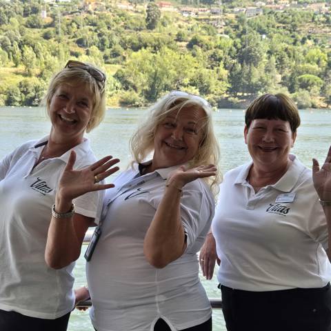 Tre af Vitus Rejsers søde, sjove og glade rejseledere står ved rælingen på et flodkrydstogtskib.