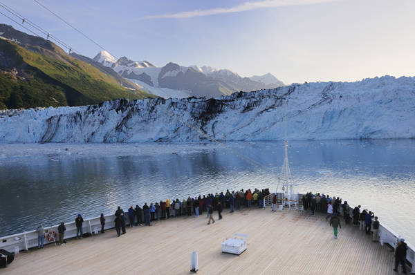 Turister står på agterdækket af et skib og betragter Hubbard gletsjeren i Alaska helt tæt på.