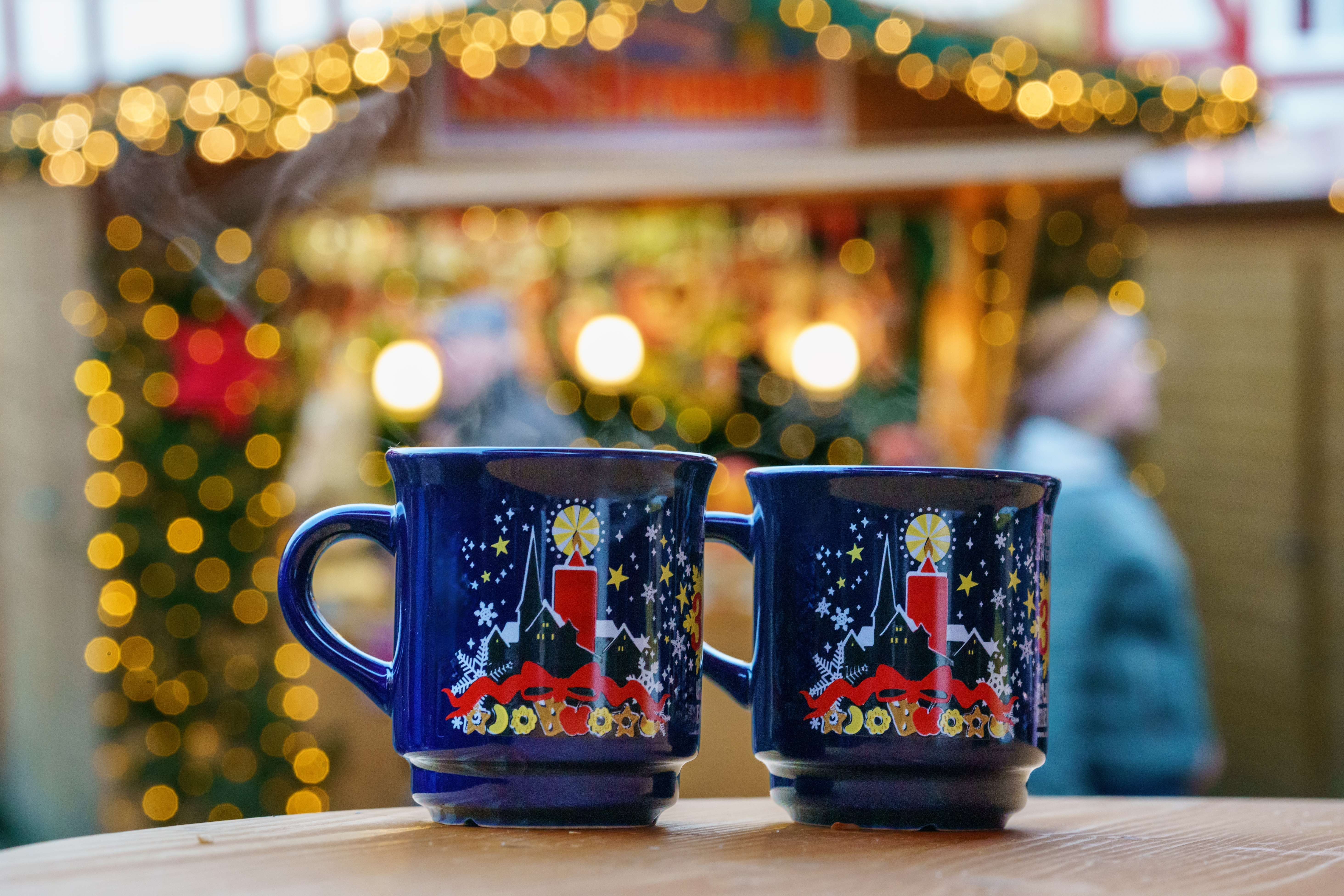 To blå krus og en julemarkedsbod i baggrunden på et julemarked i Tyskland.
