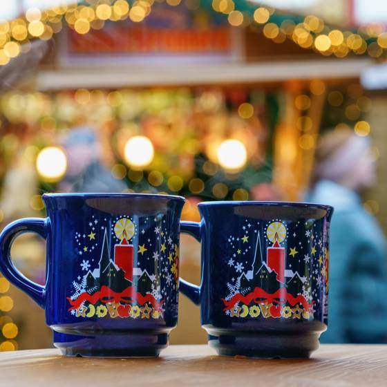 To blå krus og en julemarkedsbod i baggrunden på et julemarked i Tyskland.
