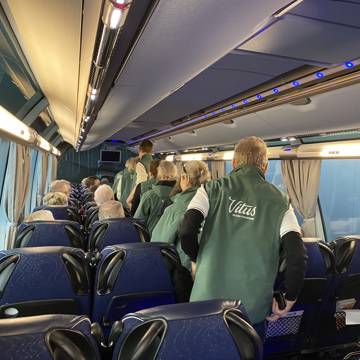 Rejselederaspiranter går gennem midtergangen på en bus.