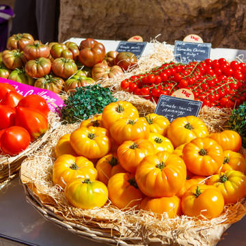 Forskellige sorter af gule, grønne og røde tomater i kurve ved en markedsbod i Italien.
