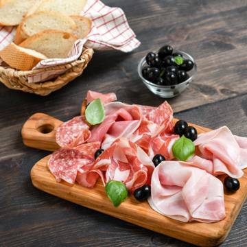 Skærebræt med anretning af charcuteri såsom salami, parmaskinke, kogt skinke og mortadella.