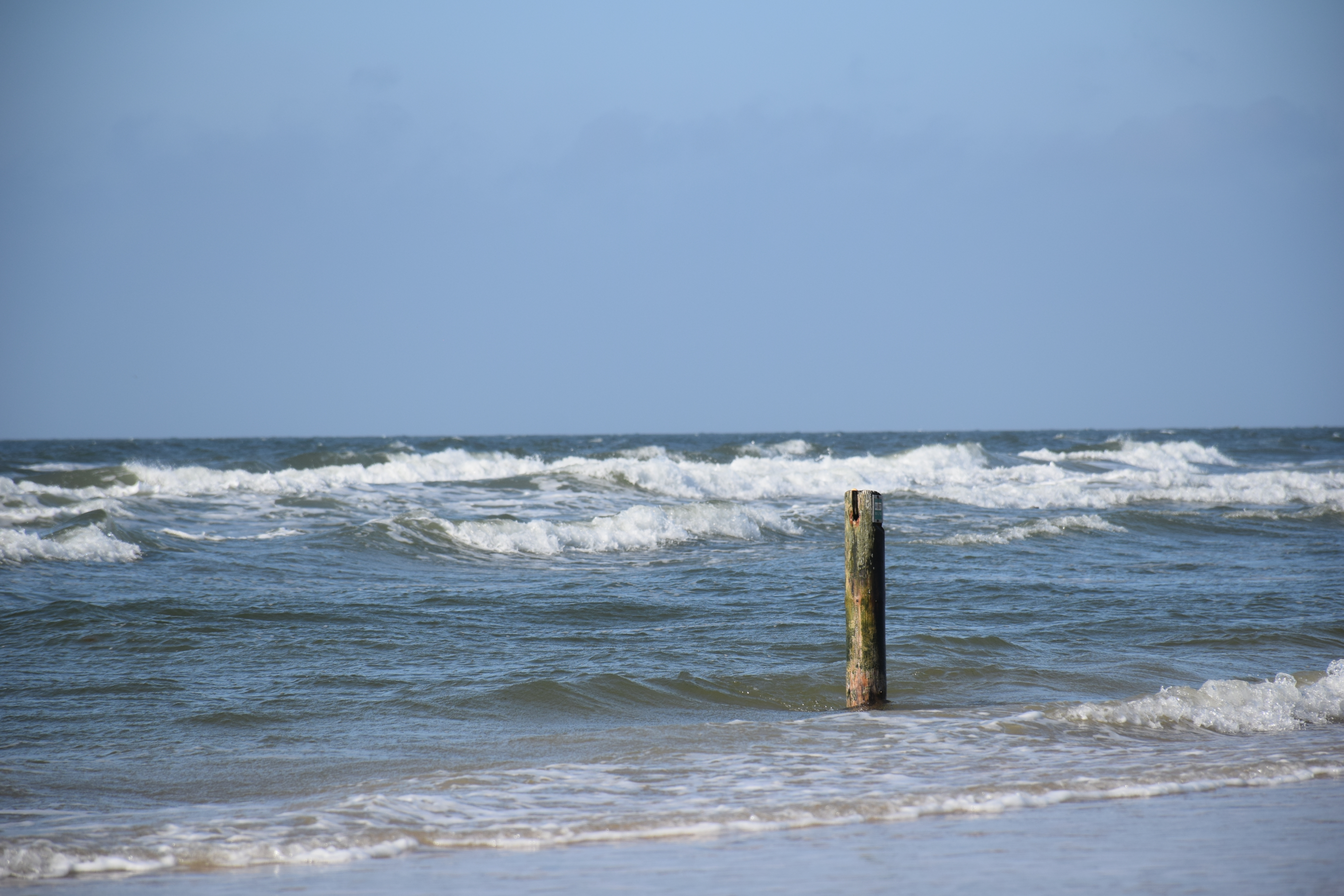 Bølger skyller op mod stranden ved havet. 