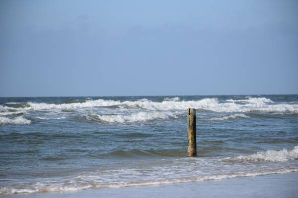 Bølger skyller op mod stranden ved havet.