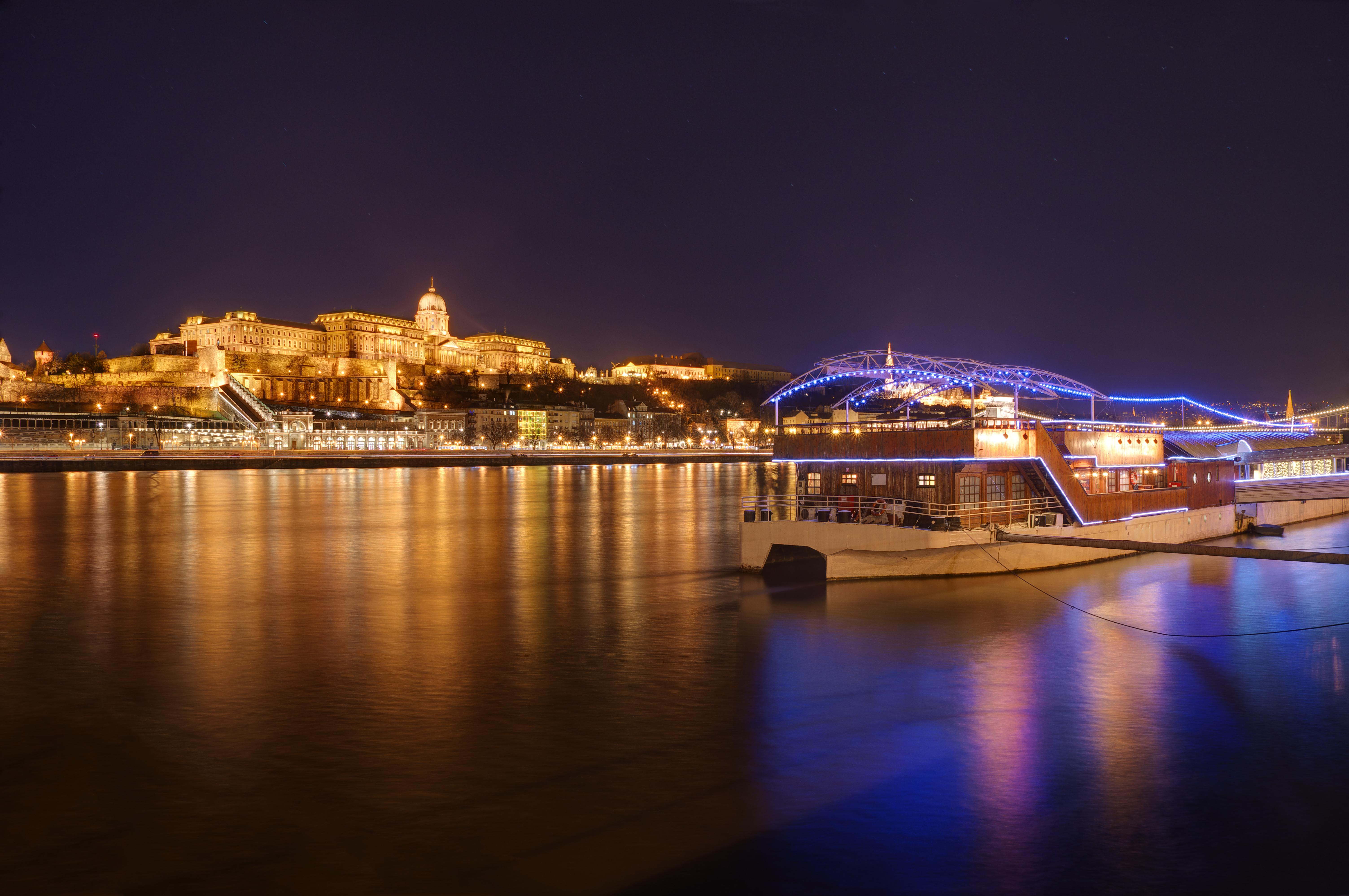 Aftenbillede af et flodkrydstogtskib ligger for kaj på Donau i Budapest.