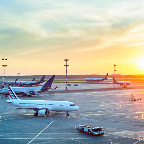 Flere fly, der taxier i lufthavnen ved solnedgang.
