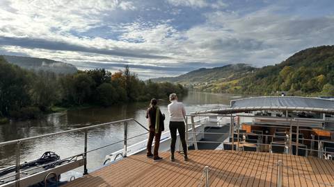 To personer nyder udsigten over landskabet ved Mosel i Tyskland fra soldækket på skibet MS Leonora.