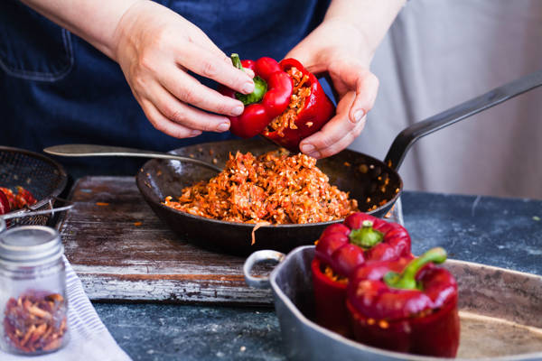 En deltager på et madlavningskursus i færd med at lave fyldte peberfrugter.