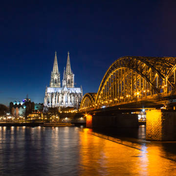 Aftenbillede af Hohenzollern-broen over Rhinen med Kölner Dom i baggrunden.