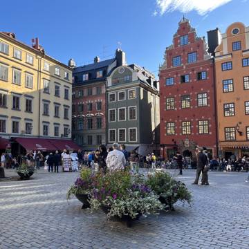 Sommerbillede af mennesker, der går på det brolagte Stortorget i Gamla Stan i Stockholm i Sverige.