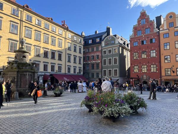 Sommerbillede af mennesker, der går på det brolagte Stortorget i Gamla Stan i Stockholm i Sverige.