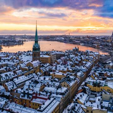 Luftfoto i aftensskumringen over Stockholm med snehvide tage.