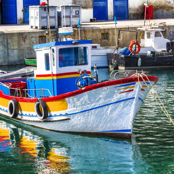 Farvestrålende lille fiskerbåd i havnen i Sesimbra i Portugal.