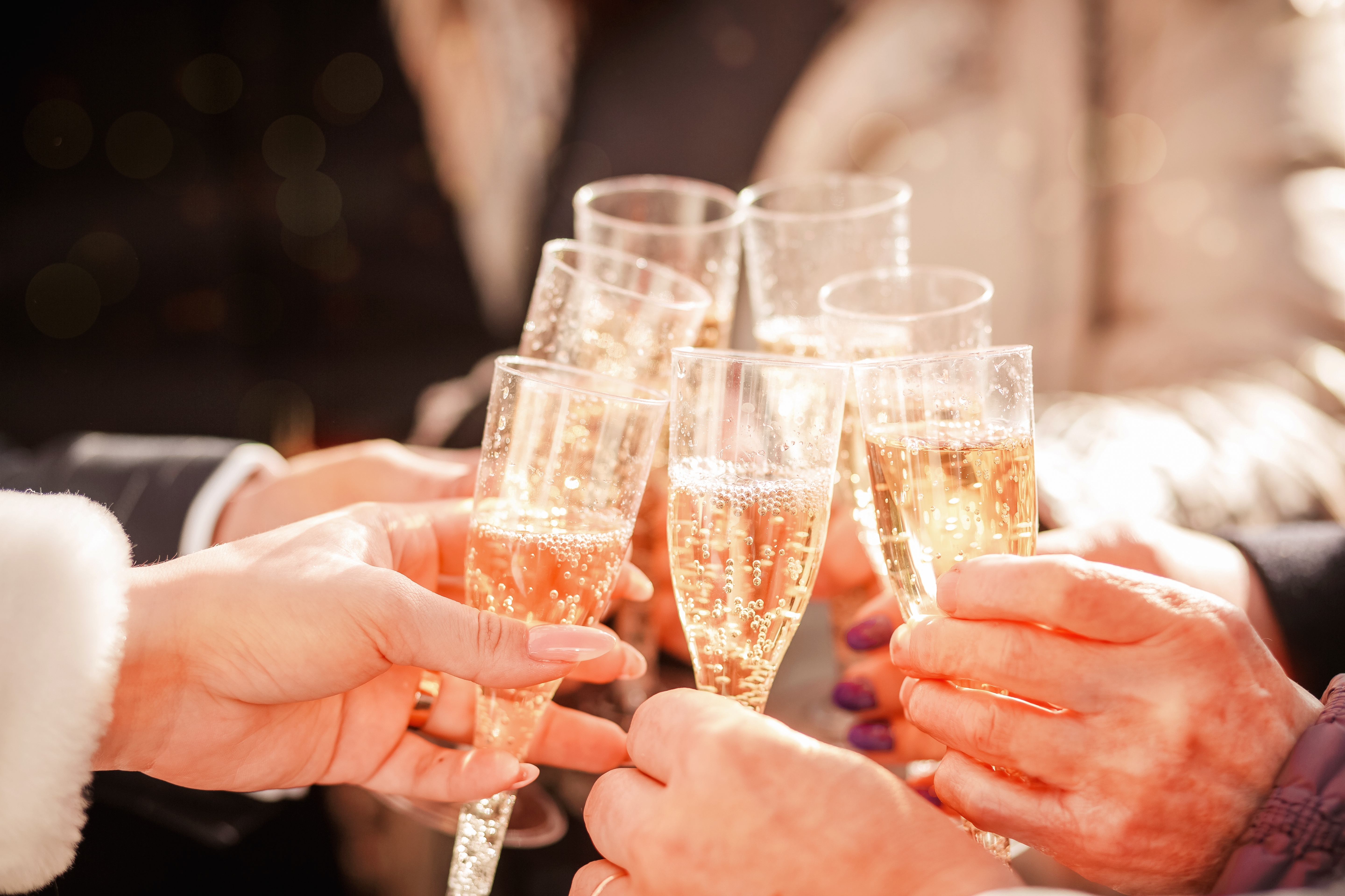 Syv hænder med champagneglas skåler.