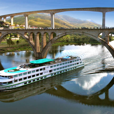 MS Vasco da Gama fra rederiet Croisi Europe sejler under en bro over Dourofloden i Portugal.