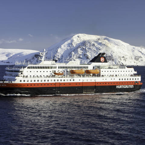 Hurtigrutens skib MS Richard With set fra siden med sneklædt kyst i baggrunden.