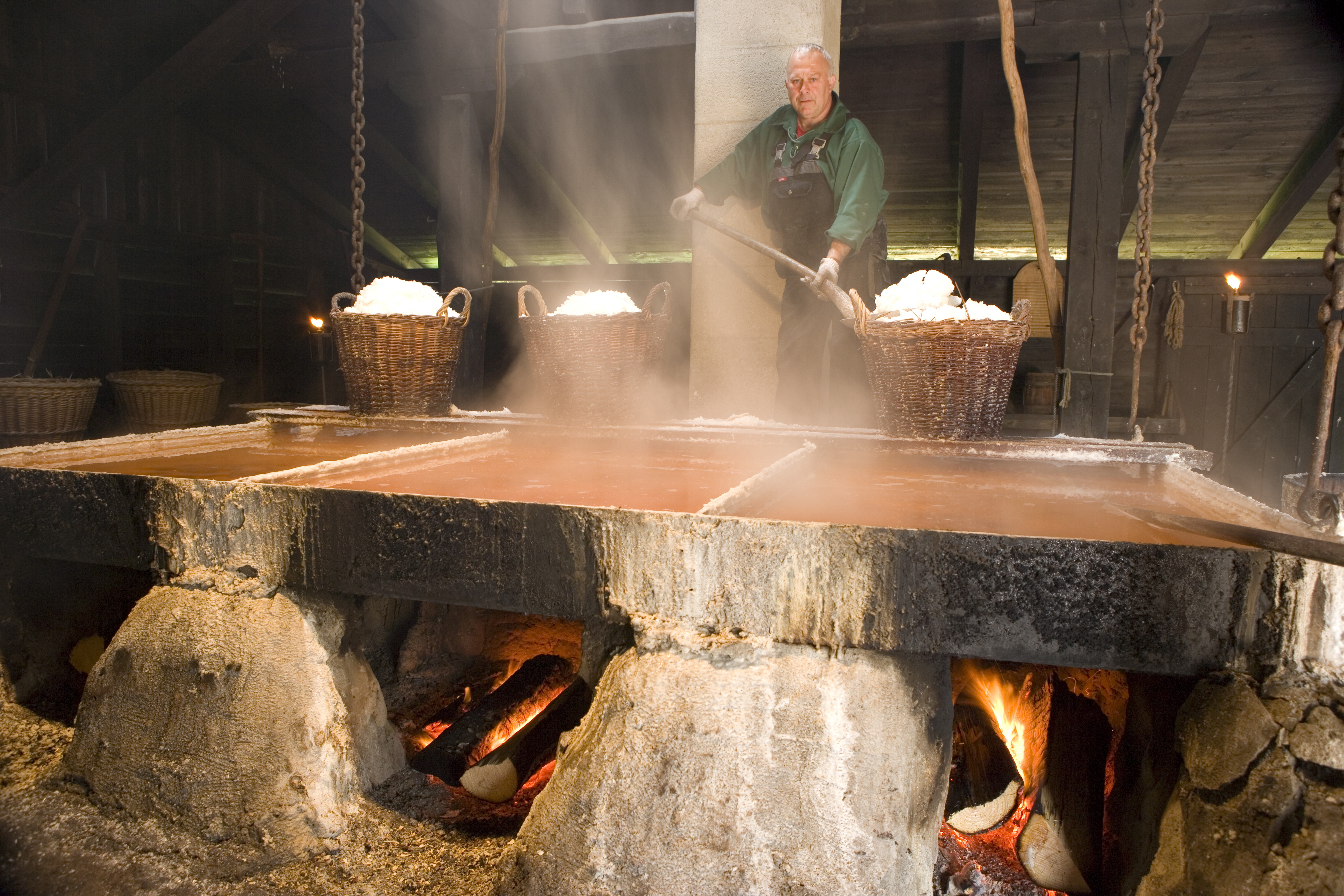 En medarbejder på Læsø Saltsyderi skovler salt i store fletkurve.