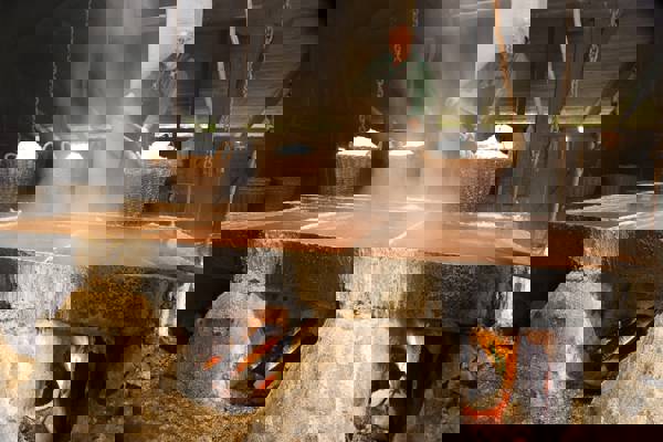 En medarbejder på Læsø Saltsyderi skovler salt i store fletkurve.