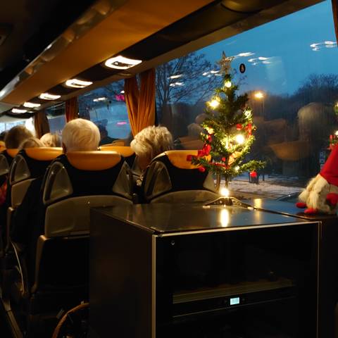Lille tændt juletræ og en nisse pynter i bussen mens rejsen går sydover til julestemning Tyskland.