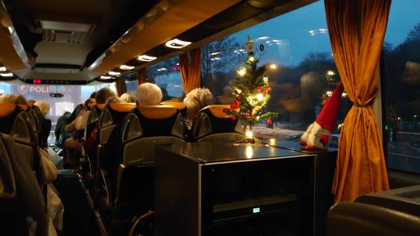 Lille tændt juletræ og en nisse pynter i bussen mens rejsen går sydover til julestemning Tyskland.