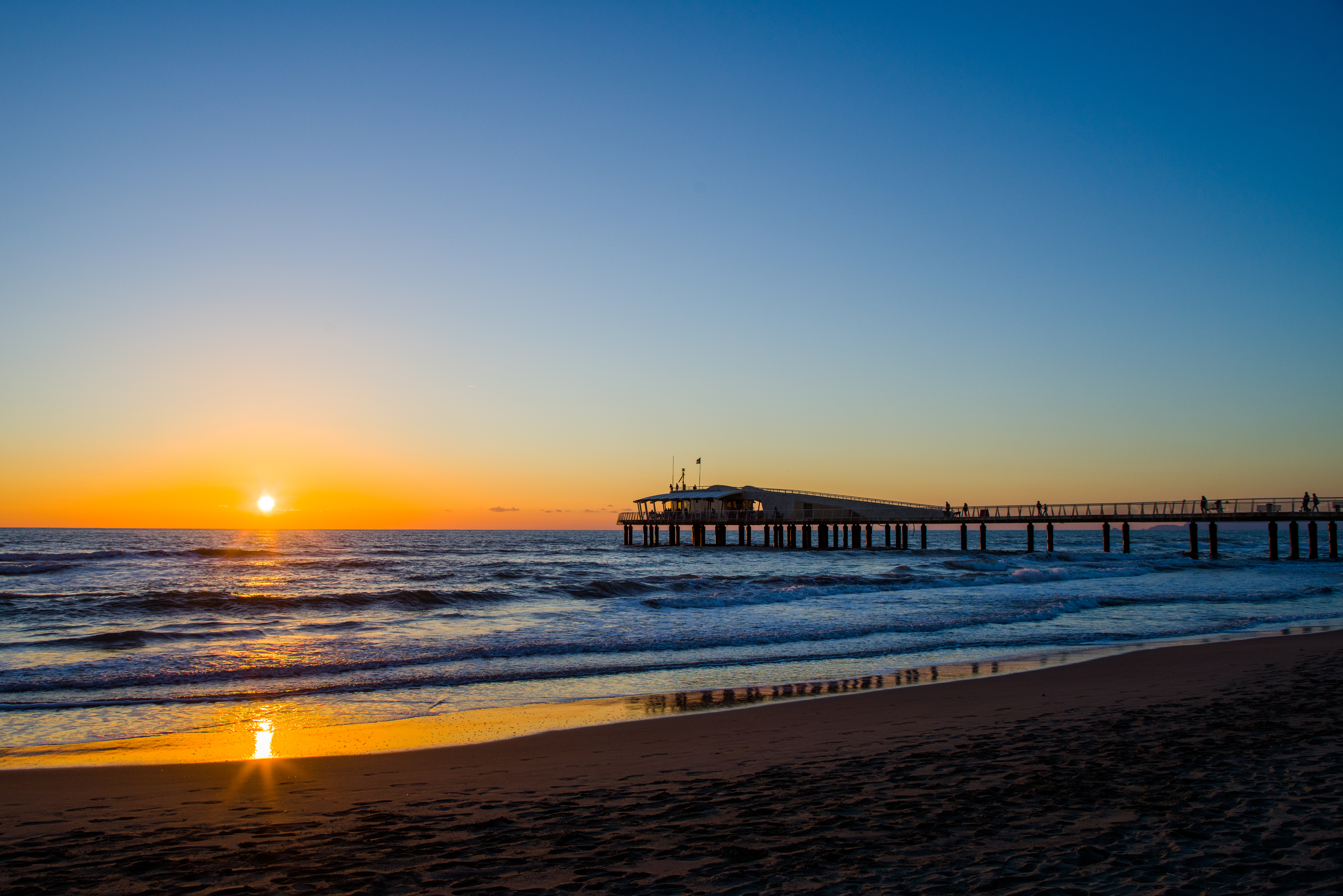 Solnedgang ved strandbro i Lido di Camaiore i Toscana i Italien.