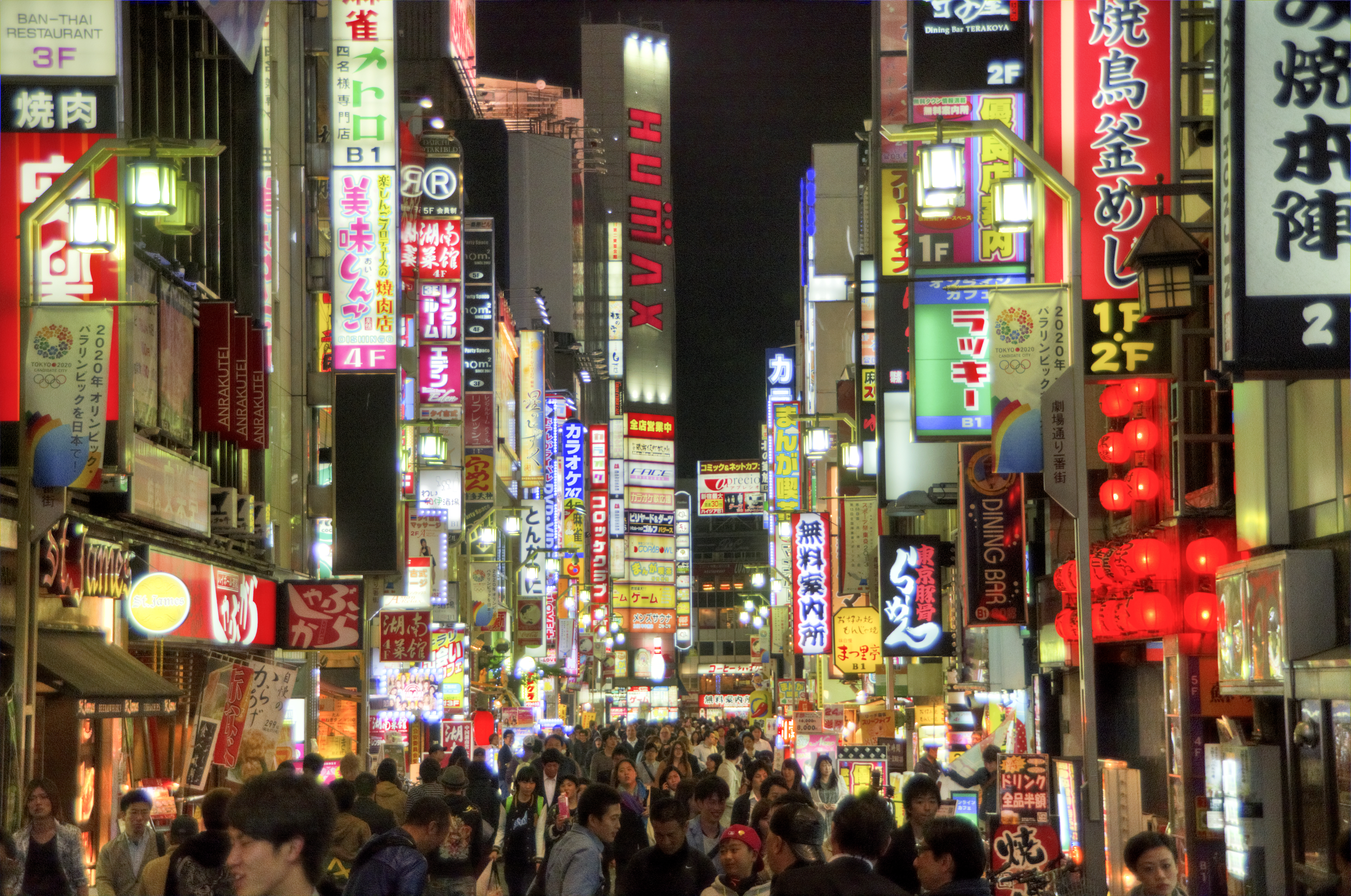 Menneskemylder og neonskilte om aftenen på en gågade i Tokyo i Japan.