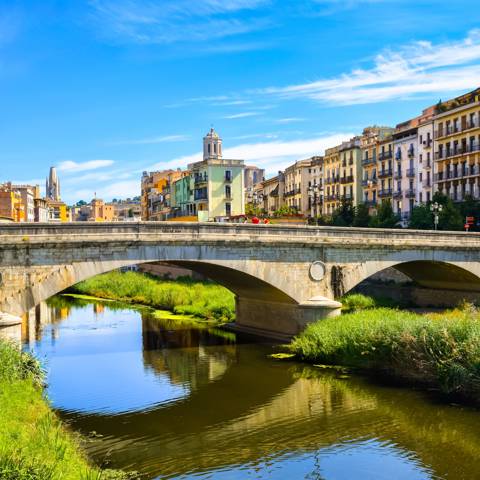 Stenbroen Pont de Pedra og de farverige gule og orange huse i Girona i Catalonien i Spanien.