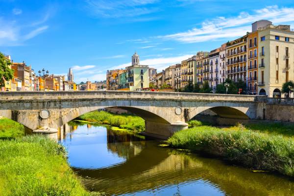 Stenbroen Pont de Pedra og de farverige gule og orange huse i Girona i Catalonien i Spanien.