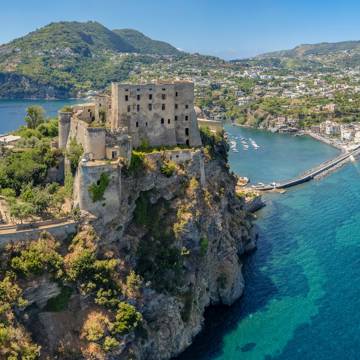 Aragonese-slottet med hovedbyen i baggrunden på Ischia i Italien.