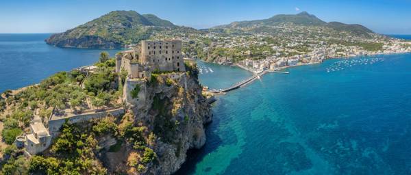 Aragonese-slottet med hovedbyen i baggrunden på Ischia i Italien.